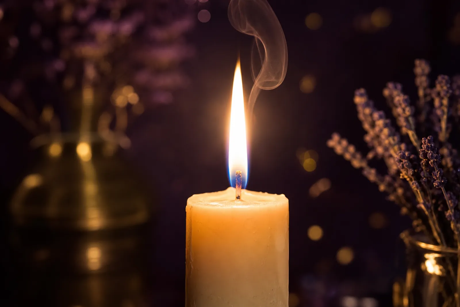 A tall, steady candle flame with a fine wisp of smoke rising above it